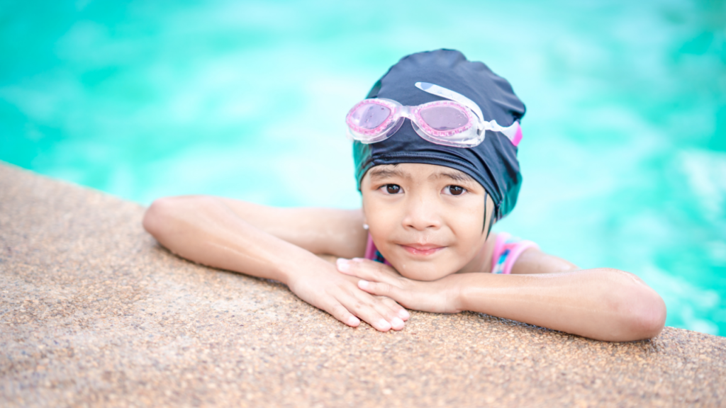 School-aged girl in swimming cap and goggles in pool