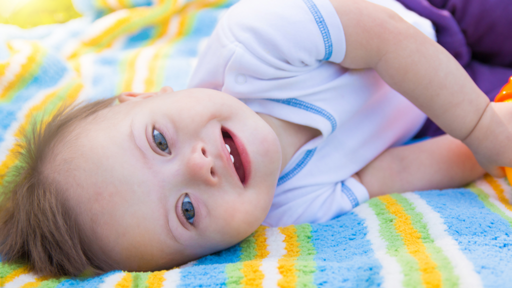 Toddler with Down syndrome lying on a colorful blanket